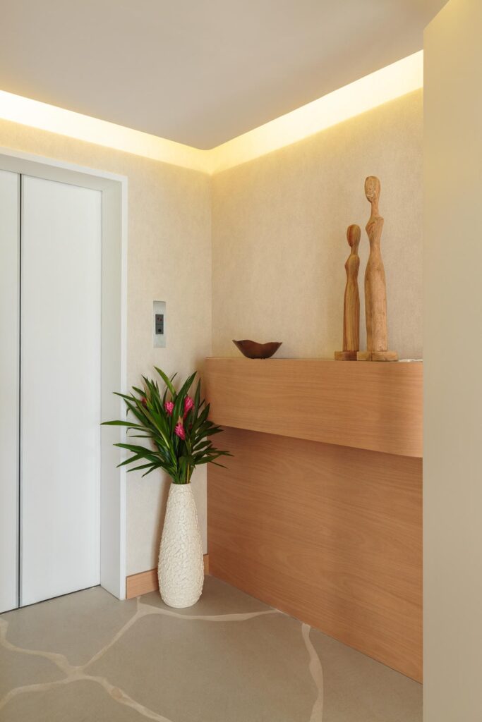Hall de entrada com painel em madeira, aparador e iluminação indireta no forro